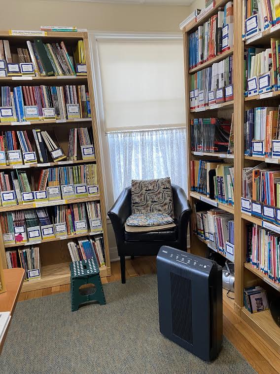 A comfy chair in a corner, surrounded by book shelves